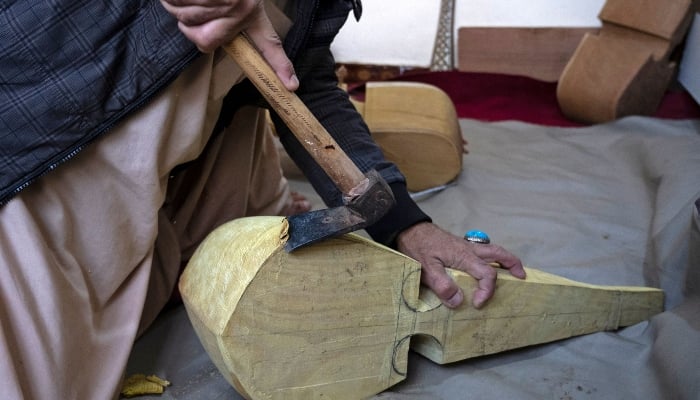 In this photograph taken on December 22, 2024, Afghan craftsman Sakhi uses a hatchet as he makes Rubab, at a workshop in Herat, Afghanistan. — AFP