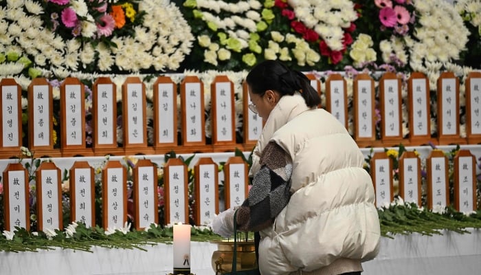 A mourner pays her respects at a memorial altar for victims of the Jeju Air plane crash, at Muan Sports Park in Muan on December 30, 2024. — AFP