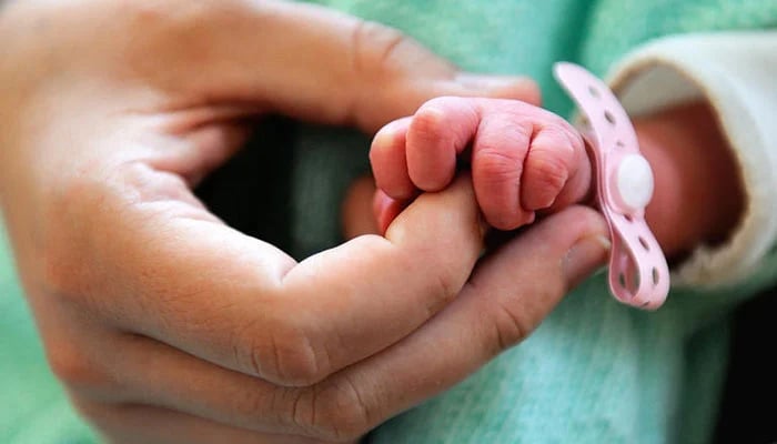 A representational image of a person holding the hand of a newborn baby. — AFP/File