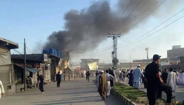 Residents gathered on a road as smoke billows after a blast at a market in Parachinar, capital of Kurram district. — AFP/File