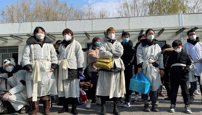 The picture shows people standing in line while wearing masks. — Reuters/File