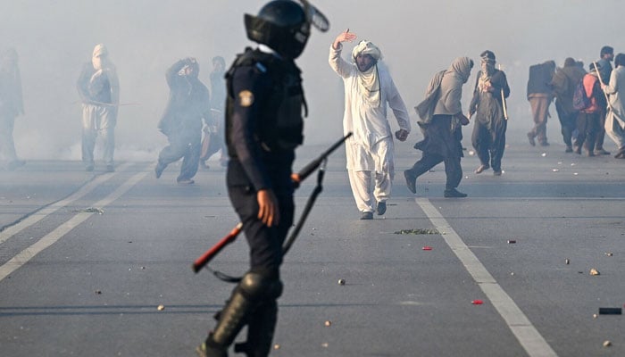 A PTI supporter gestures as police fire tear gas shells to disperse the crowd in Islamabad on Nov 26. — AFP