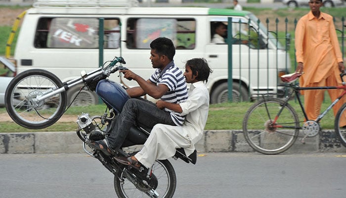 Youths on motorcycles perform street stunts in Islamabad. —AFP/File