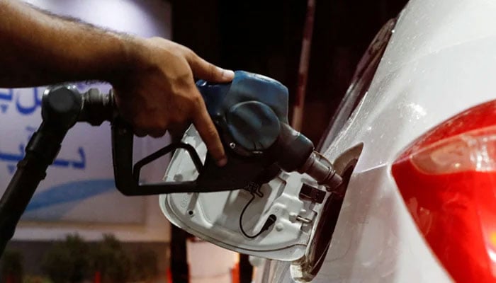 A worker holds a fuel nozzle to fill fuel in a car at petrol station in Karachi, on September 16, 2023. — Reuters