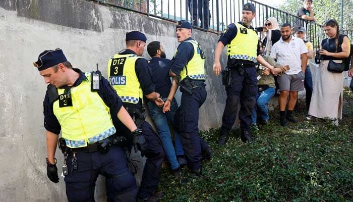 Police officers intervene after the reaction of the peoples as protesters burn the Sacred Qur'