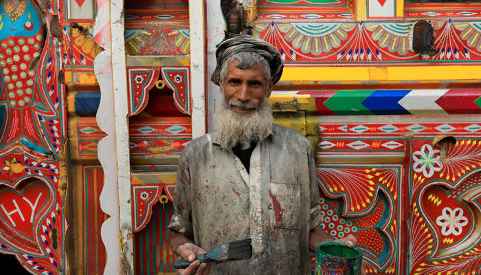 A truck art painter, poses in front of a decorated supply truck in a workshop in Peshawar on November 23, 2023. — Reuters