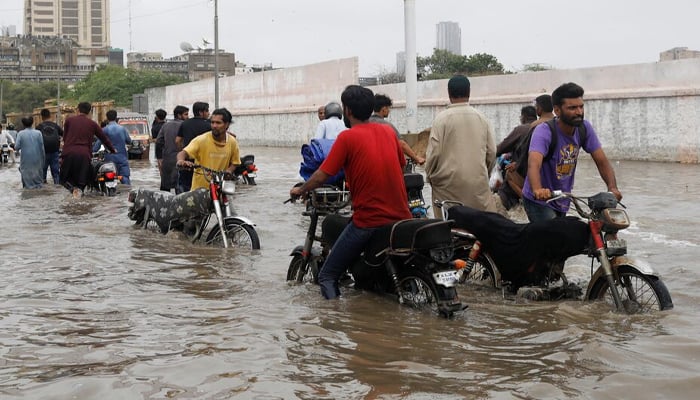 ] Residents commute through a flooded road during the monsoon season in Karachi, Pakistan July 9, 2022.